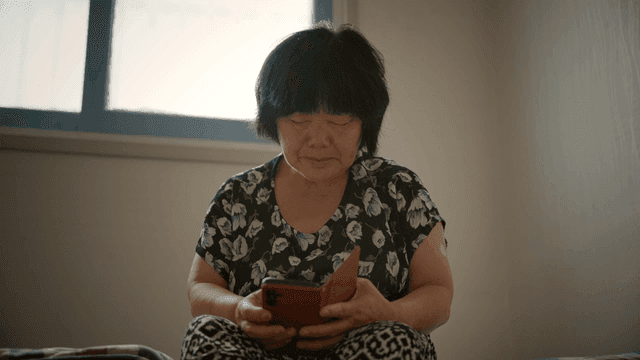 실내에서 스마트폰을 사용하는 노인 여성