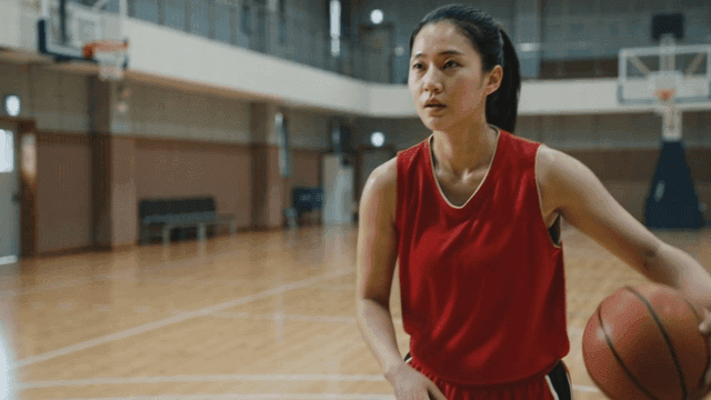 Woman practicing basketball in indoor gym