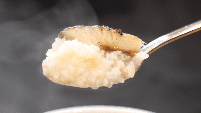 Spoonful of grilled fish in steaming rice water