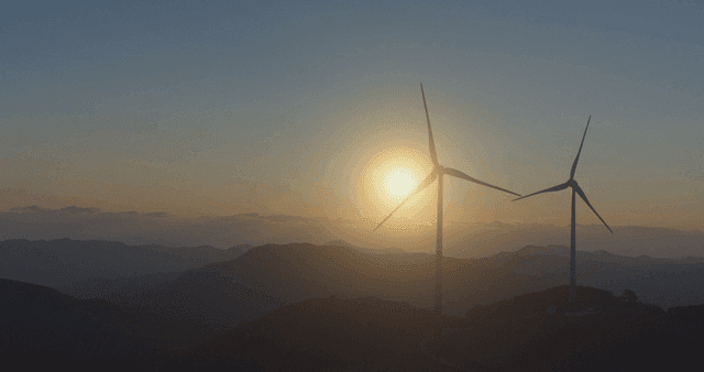 Sunrise beside rotating wind turbines