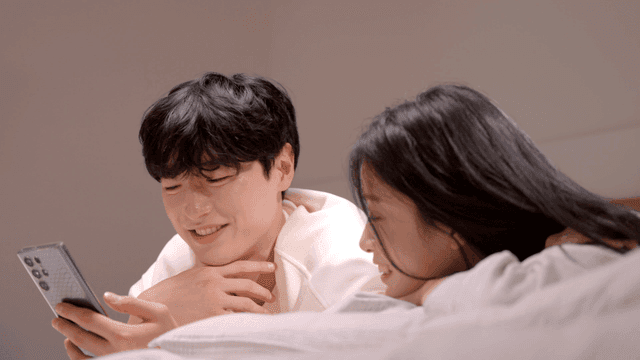 Couple relaxing together while looking at smartphone