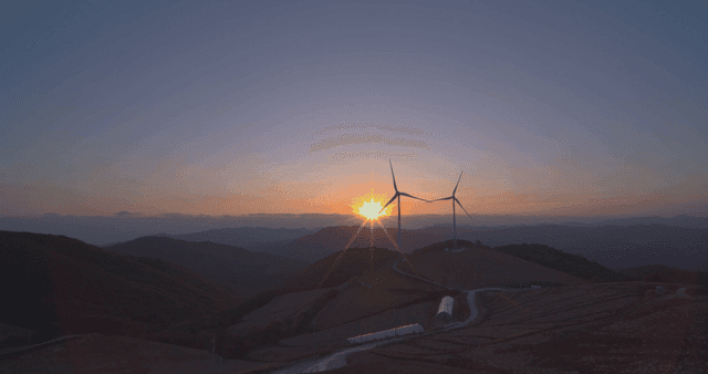 언덕 밭 위의 풍력 터빈 옆 일출