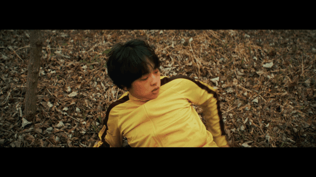 노란 트레이닝복을 입고 낙엽 위에 누운 사람