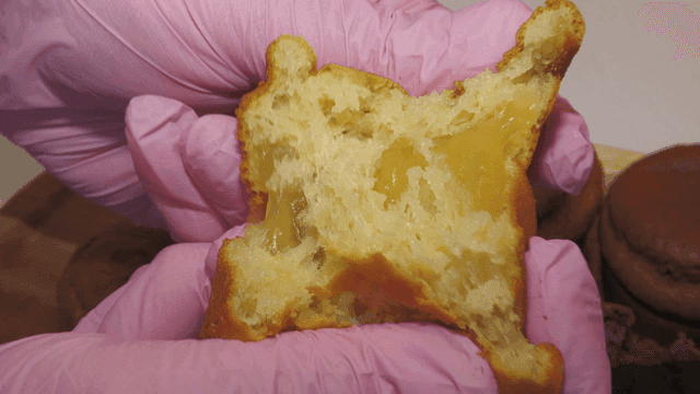 Hands in pink gloves breaking a pastry