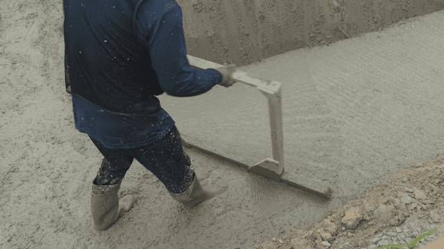 작업자가 젖은 콘크리트 표면을 고르는 모습