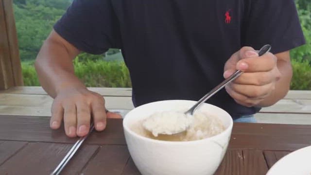 Person enjoying a meal with kimchi and riceoutdoors with a serene background
