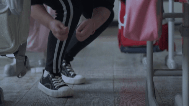 Child picking up trash from the classroom floor and putting it in a bag