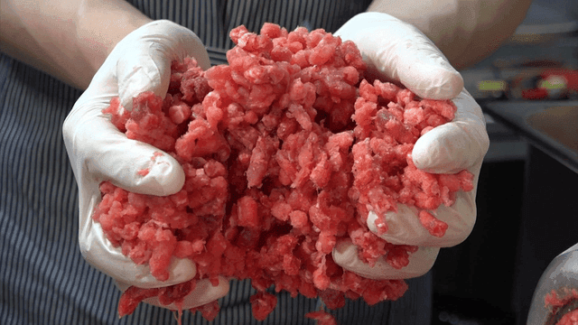 장갑을 낀 손이 다진 고기를 다루는 모습