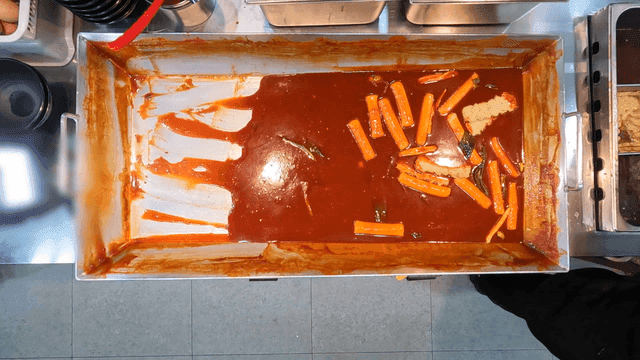Tteokbokki being emptied from large iron plate