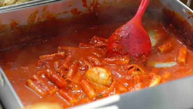 Cooking tteokbokki in a large metal tray