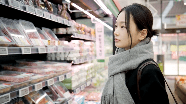 Young woman choosing meat at supermarket
