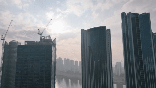 구름 낀 하늘 아래 고층 건물과 크레인