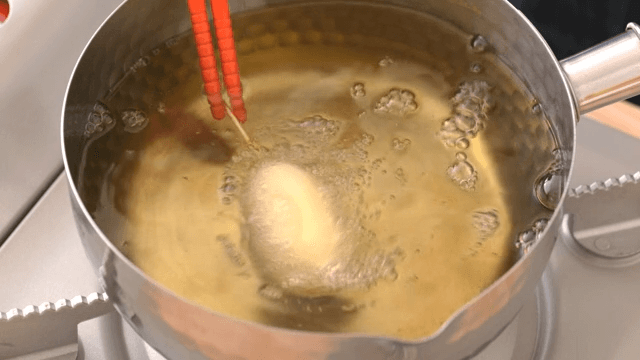 Deep frying food in oil with chopsticks