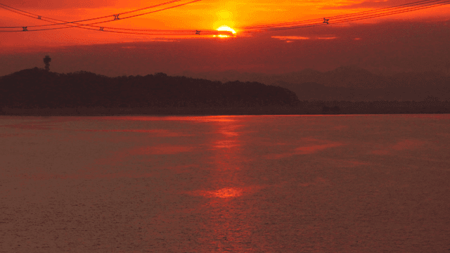 전선이 있는 고요한 호수 위의 일몰