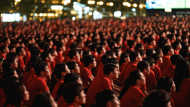 Large crowd wearing red shirts watching event
