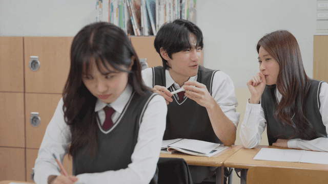 Two students laughing in the back while the student in front looks tense