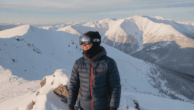 눈 덮인 산 정상에 올라 만세하는 남자