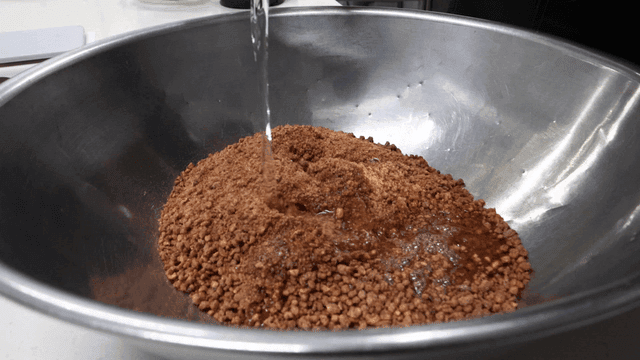 Measuring cup for pouring liquid into bowl containing ingredients