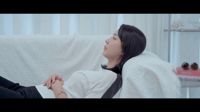Woman looking at her phone while lying on white sofa and resting.