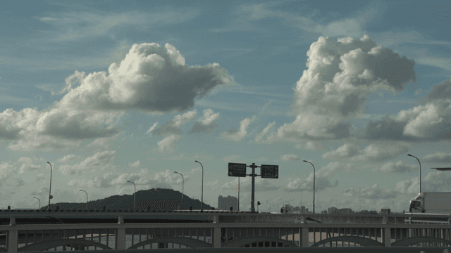 White cloudy sky above bridge with moving vehicles