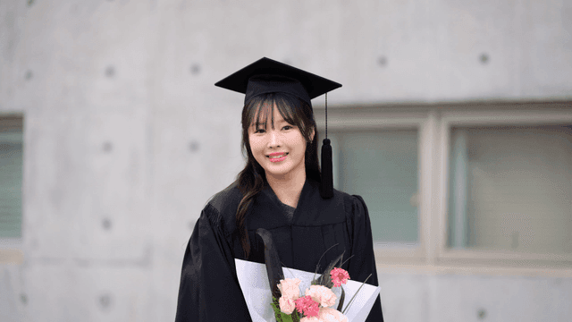 Graduate holding flowers with a smile