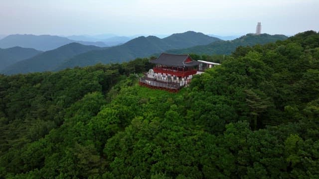 Traditional Korean pavilion on top of a green mountain