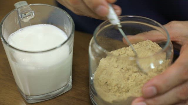 Adding Roasted Grain Powder to a Glass Filled with Milk