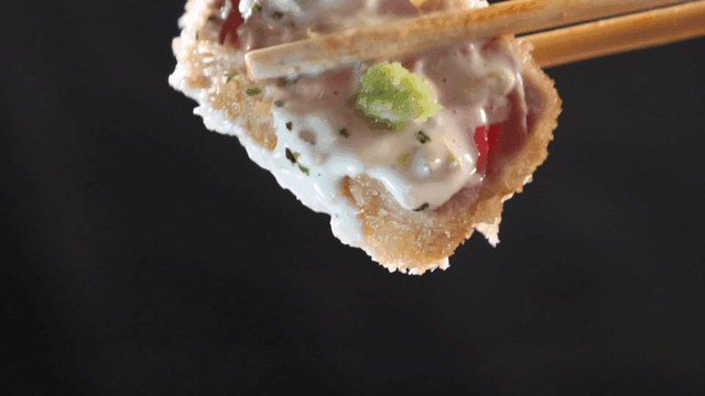 Chopsticks lifting tuna cutlet topped with wasabi