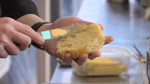 신선한 크루아상에 버터를 바르는 모습