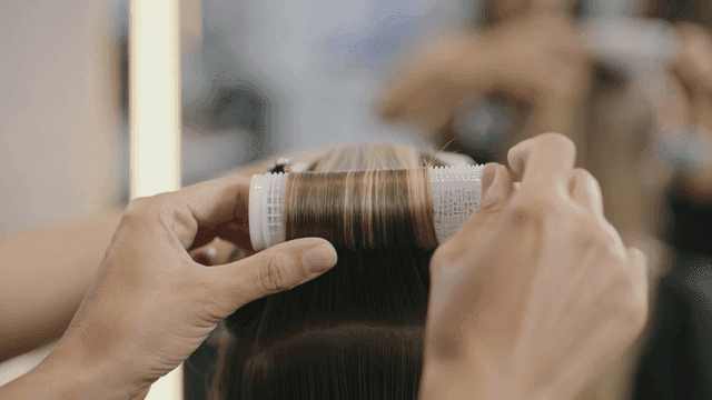 Woman rolling her hair with hair rollers at hair salon