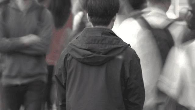 Back of lonely man in passing crowd