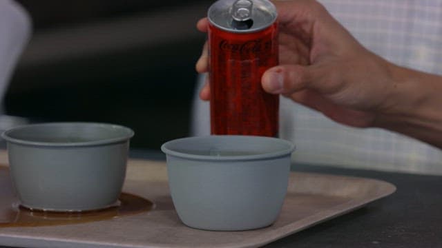 Pouring canned cola into a gray cup