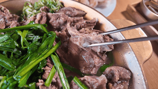 Chopsticks picking up beef short rib stew boiled with chives