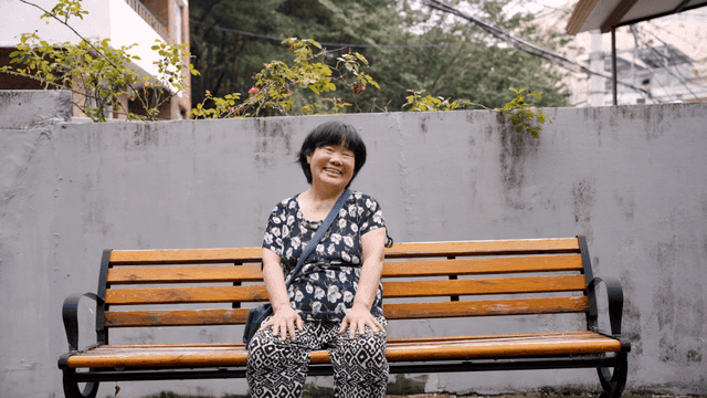 벤치에 앉아 미소 짓는 노인 여성