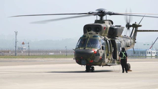 A military helicopter being prepared for takeoff on a clear day