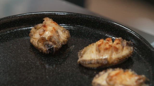 검은 철판 위에 올라가는 전복 구이