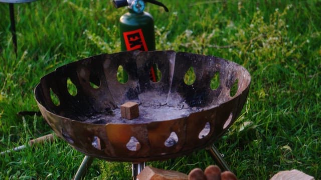 풀밭 위 화로에 토치로 불을 붙이는 모습