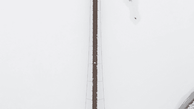 People walking on bridge over snow-covered lake