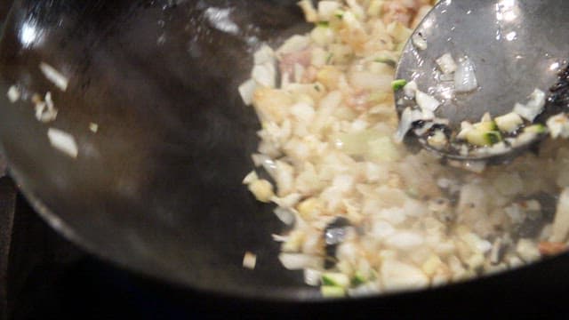 Stir-frying chunjang sauce, vegetables, and minced meat in a hot wok