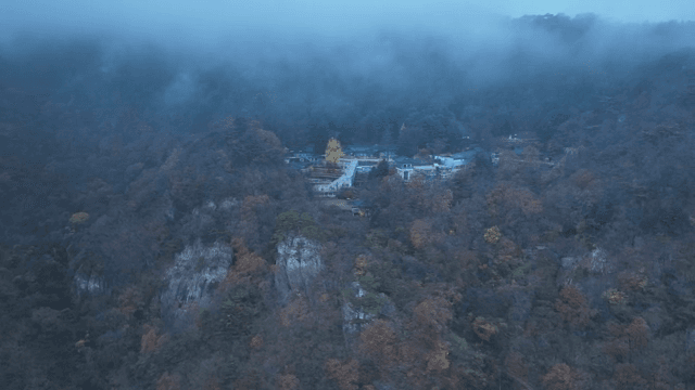 Misty mountain landscape with a distant hanok