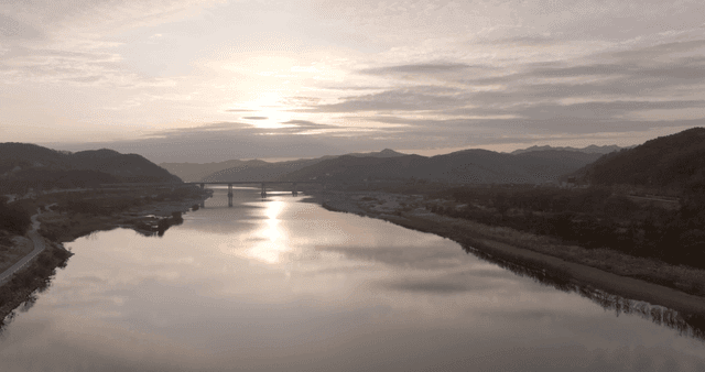 A tranquil river at sunrise with mountains