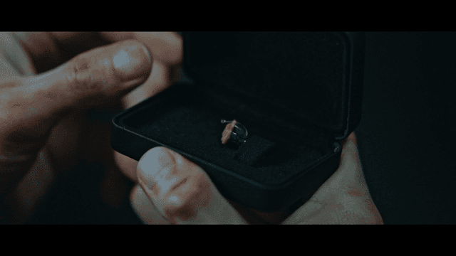 A person holding a ring box with a ring