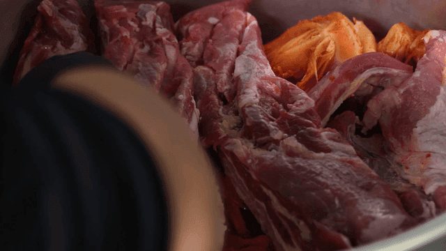 Kimchi and pork being prepared in a pot