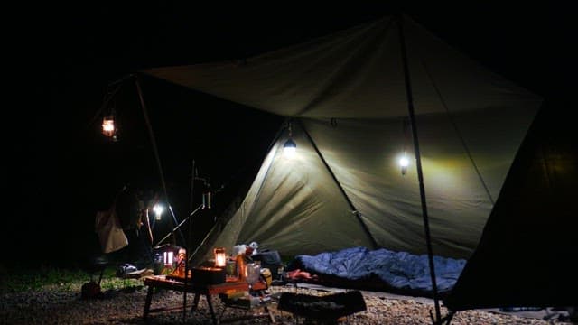 Cozy night camping scene with lantern and equipment