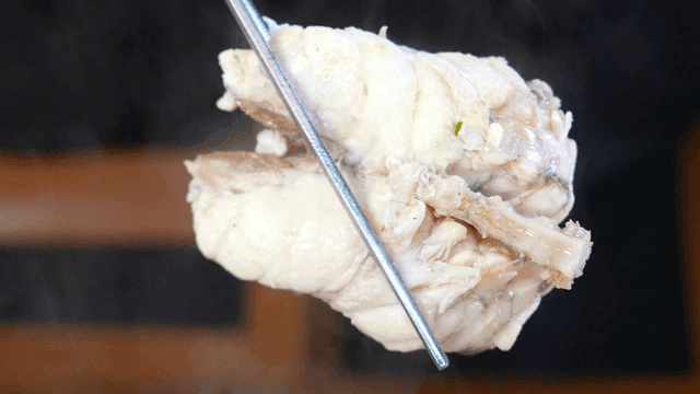 Chopsticks picking up fish meat in pufferfish clear soup