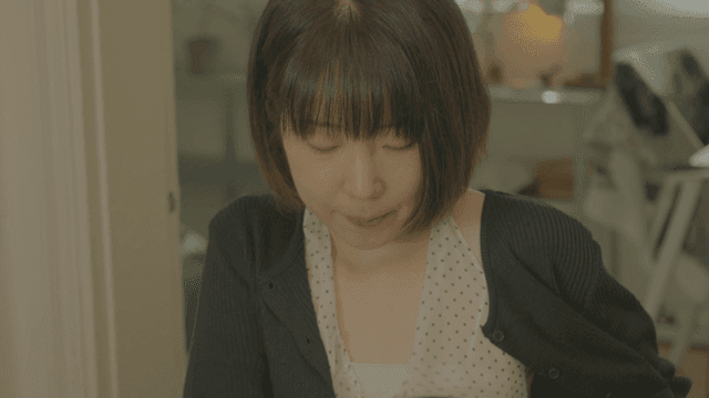 의자에 앉으며 어색하게 미소를 짓는 단발머리 여성