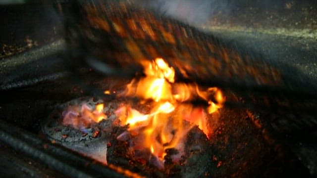 Charcoal-grilling pork belly over open flame