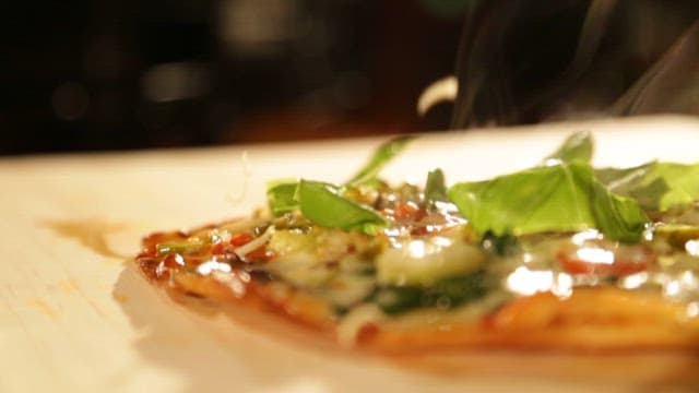 갓 구워진 피자 위에 치즈를 뿌리는 장면