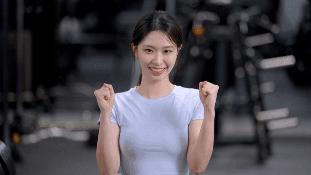 헬스장에서 정면을 보고 주먹을 모아 화이팅하는 젊은 여성