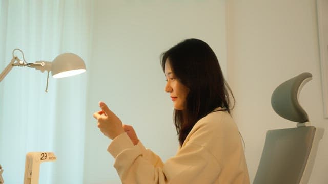 Woman using a smartphone at a desk in a calmly lit room